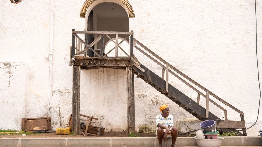 A Ghanaian cook preparing groundnut soup over open charcoal.